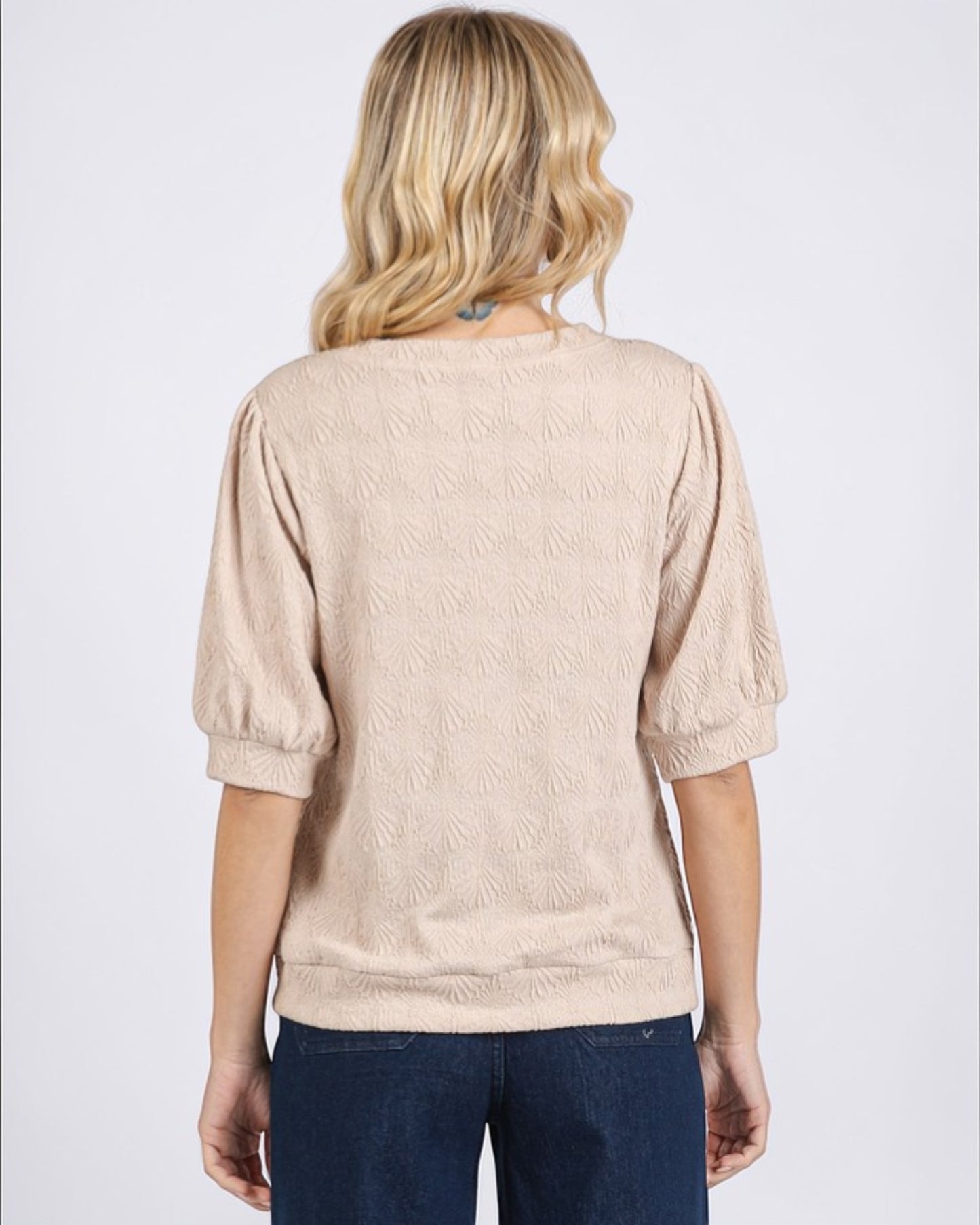 Person wearing a beige textured sweater on a white background