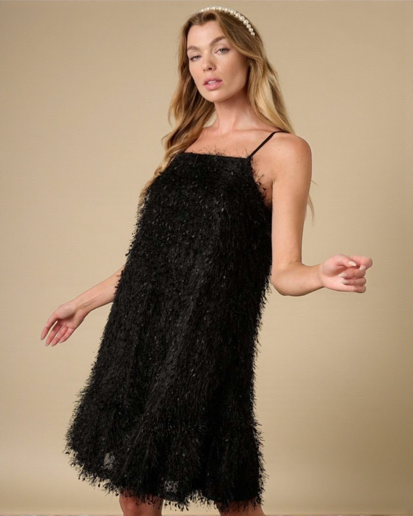 Woman wearing a black sequin dress against a beige background