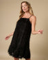 Woman wearing a black sequin dress against a beige background