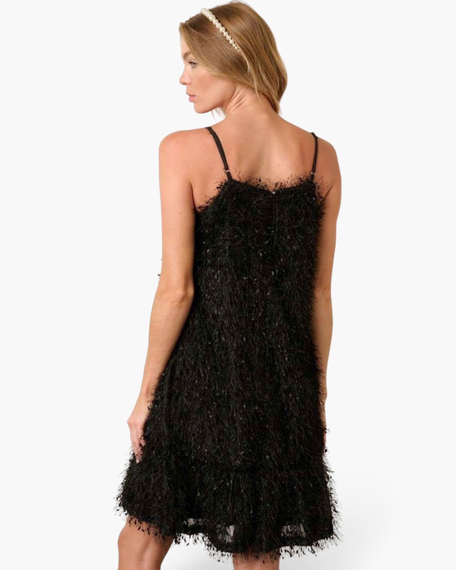 A woman wearing a black feather-textured spaghetti-strap dress, shown from the back against a plain white studio background.