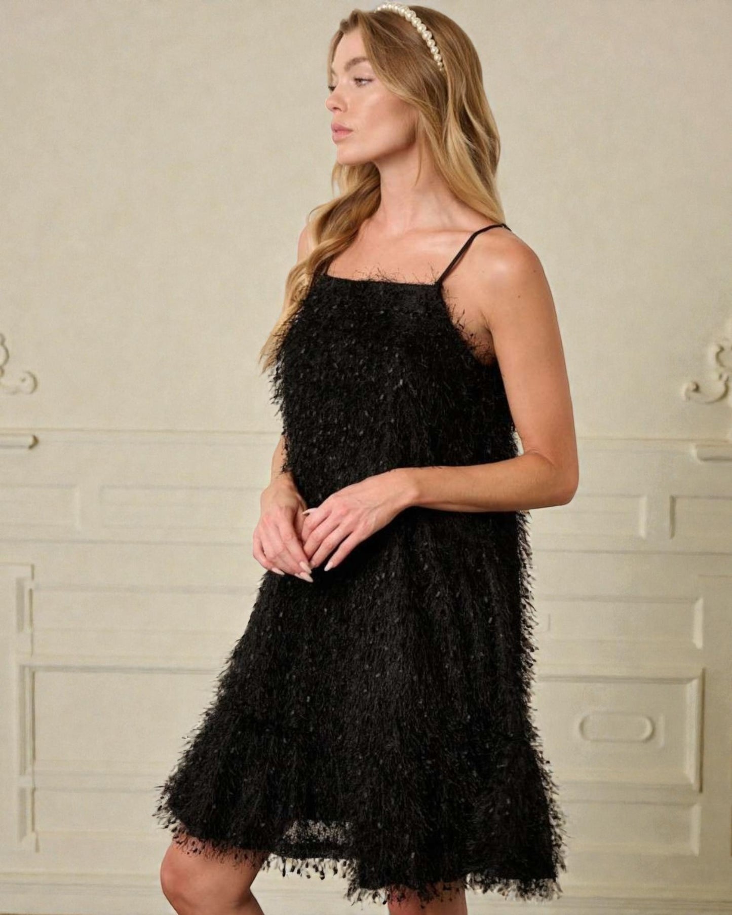 Woman wearing a black lace dress against a neutral background