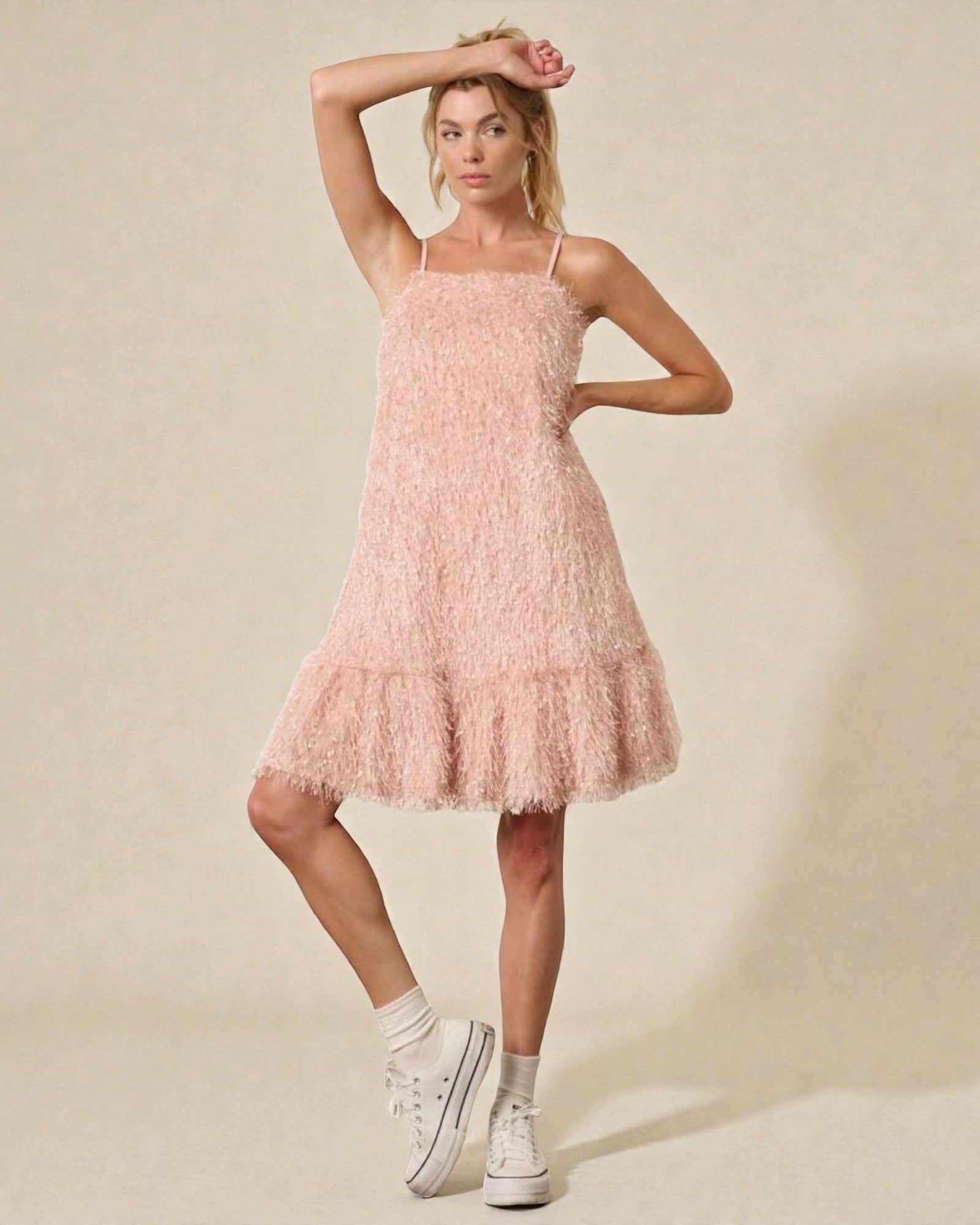 Woman wearing a pink dress with white sneakers on a beige background