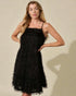 Woman wearing a black lace dress against a beige background
