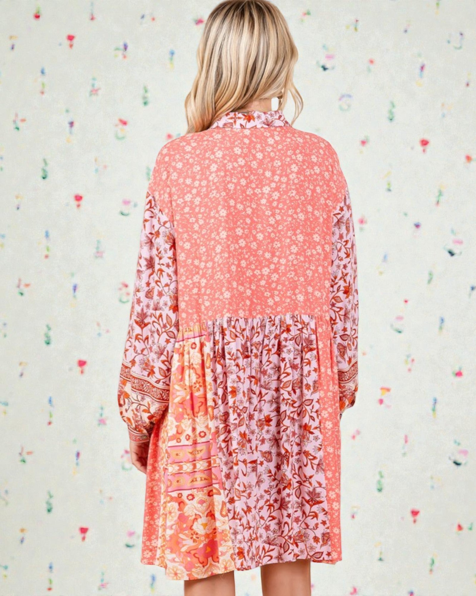 Woman wearing a coral floral dress against a light background with colorful heart patterns.