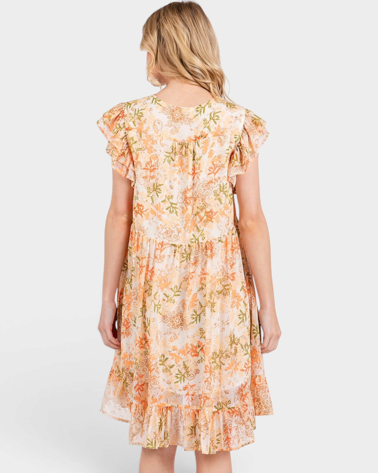 Woman wearing a floral dress with ruffled sleeves on a white background