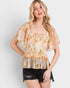 Woman wearing a floral blouse with ruffled sleeves on a plain background