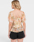 Woman wearing a floral blouse and black shorts on a white background