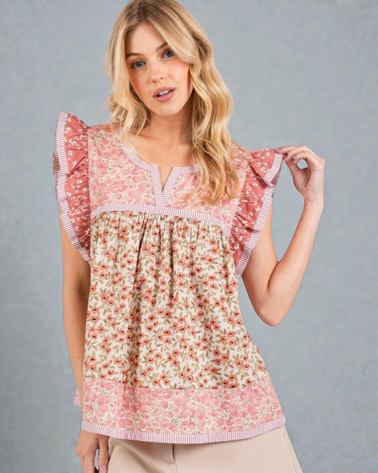 Woman wearing a floral blouse with ruffled sleeves against a gray background