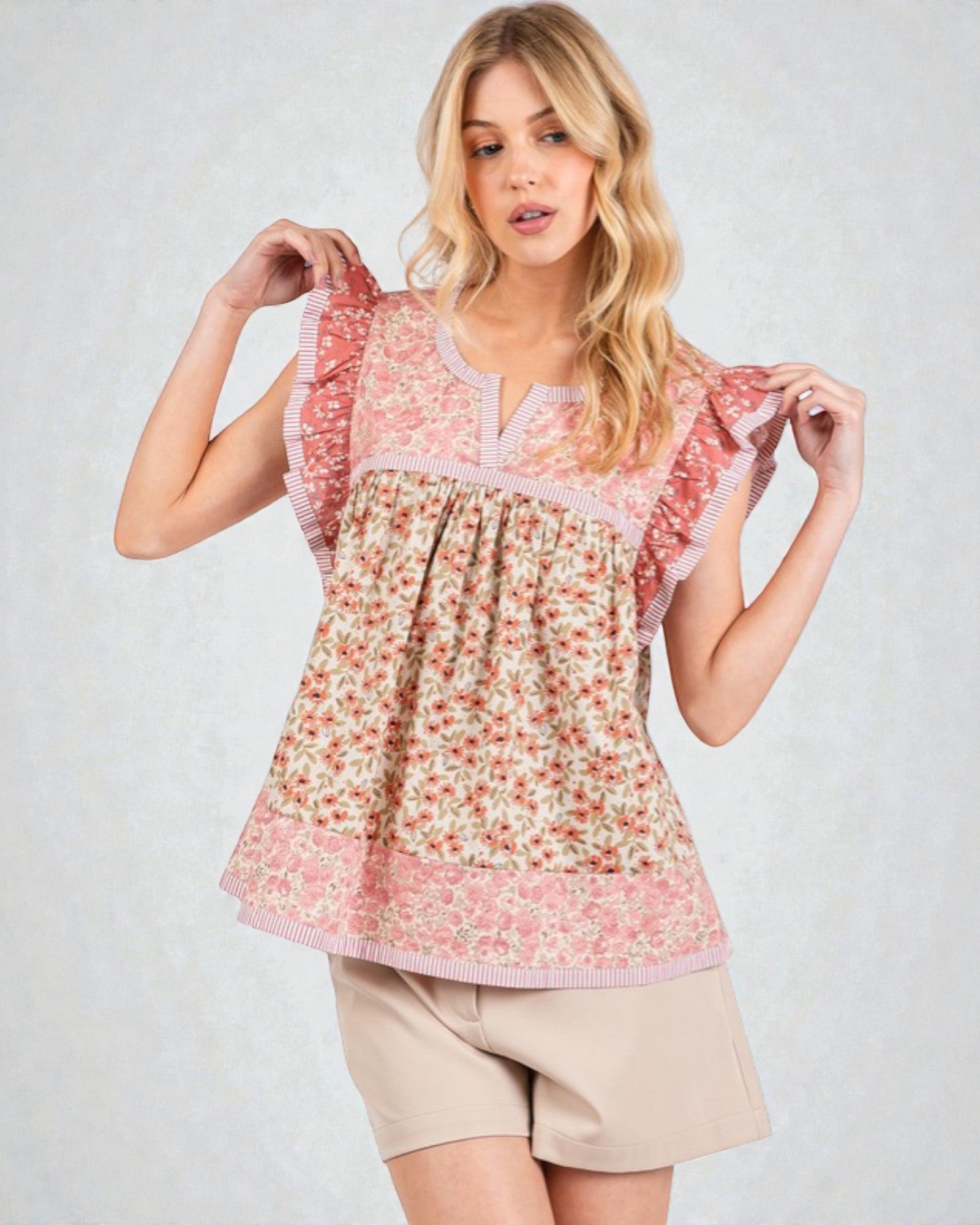 Woman wearing a floral blouse with ruffled sleeves on a plain background