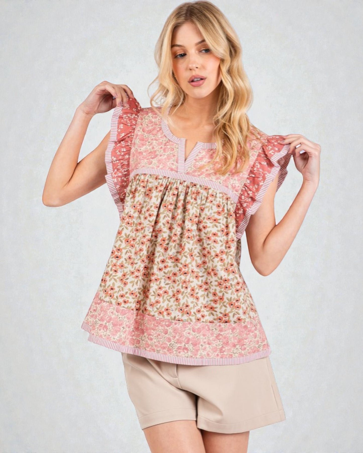 Woman wearing a floral blouse with ruffled sleeves on a plain background