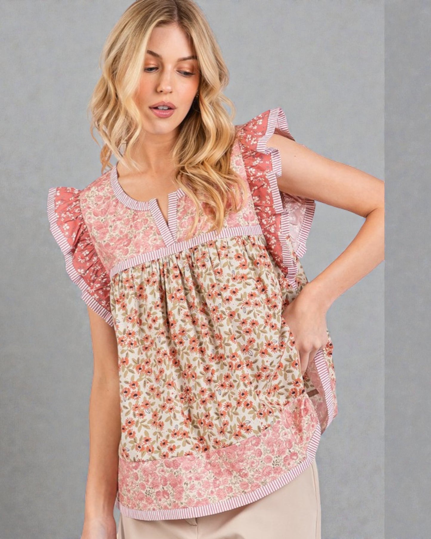 Woman wearing a floral blouse with ruffled sleeves against a gray background