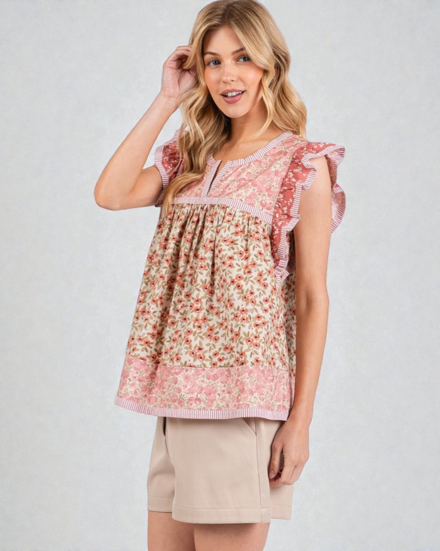 Woman wearing a floral blouse with ruffled sleeves on a plain background