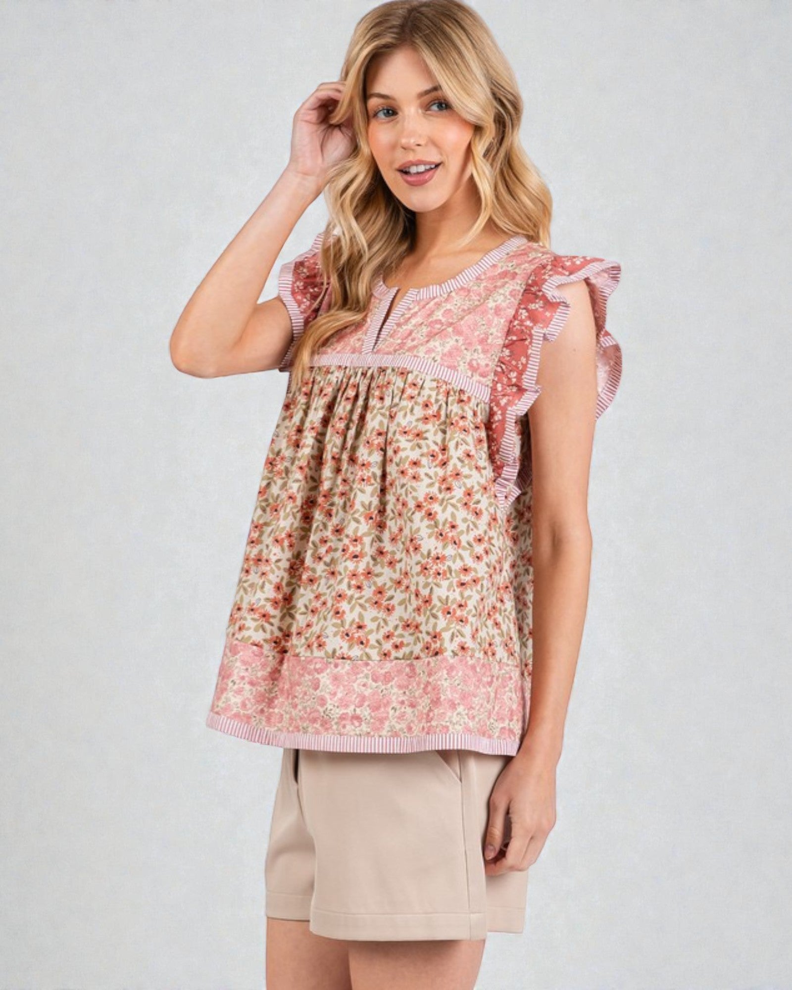 Woman wearing a floral blouse with ruffled sleeves on a plain background