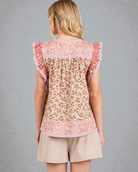 Woman wearing a floral top and beige shorts against a gray background