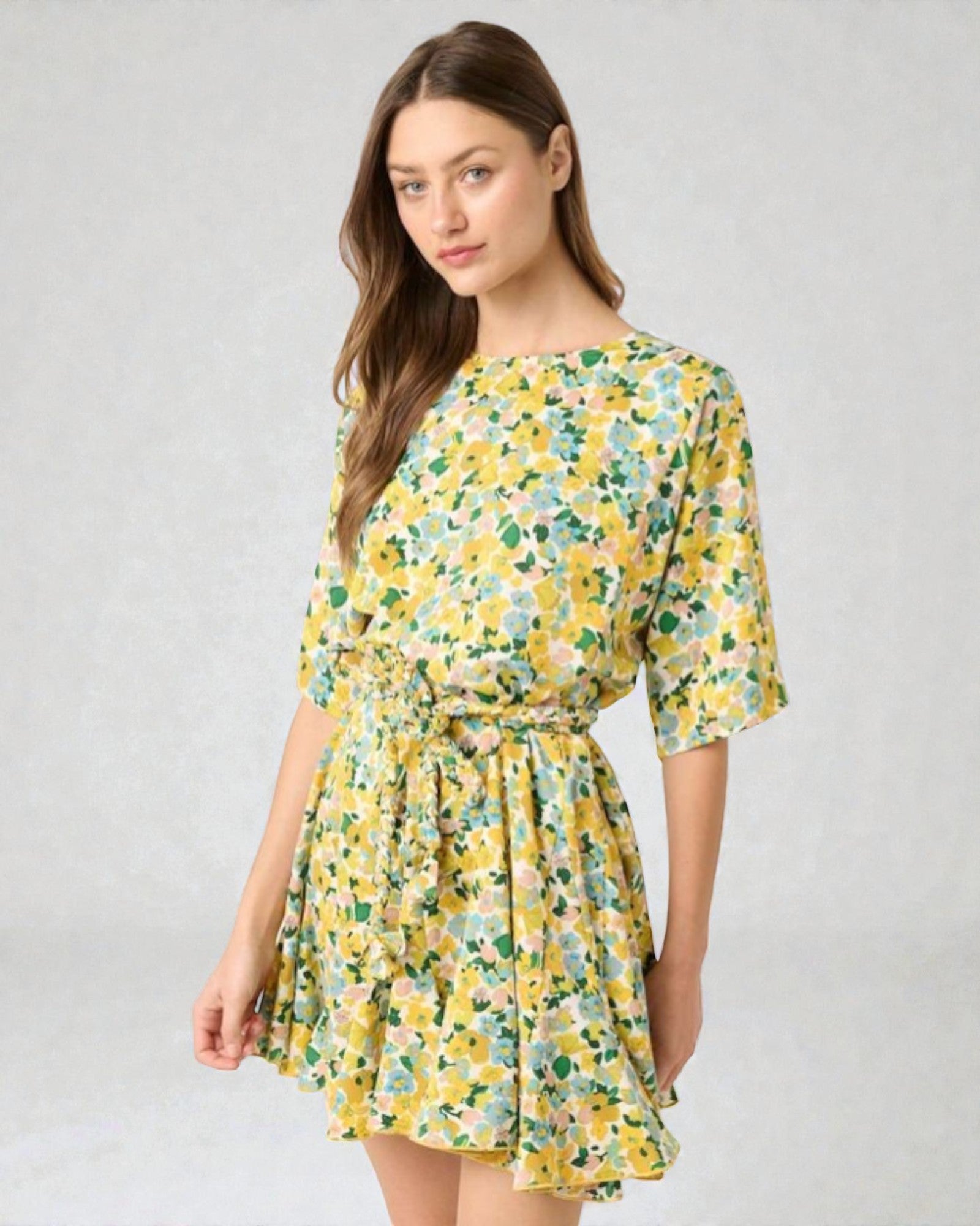 Woman wearing a yellow floral dress on a gray background