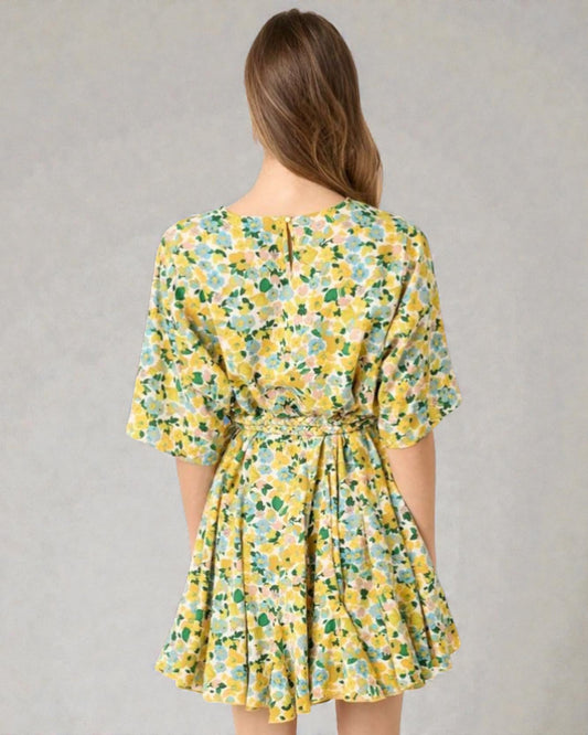 Woman wearing a yellow floral dress against a gray background