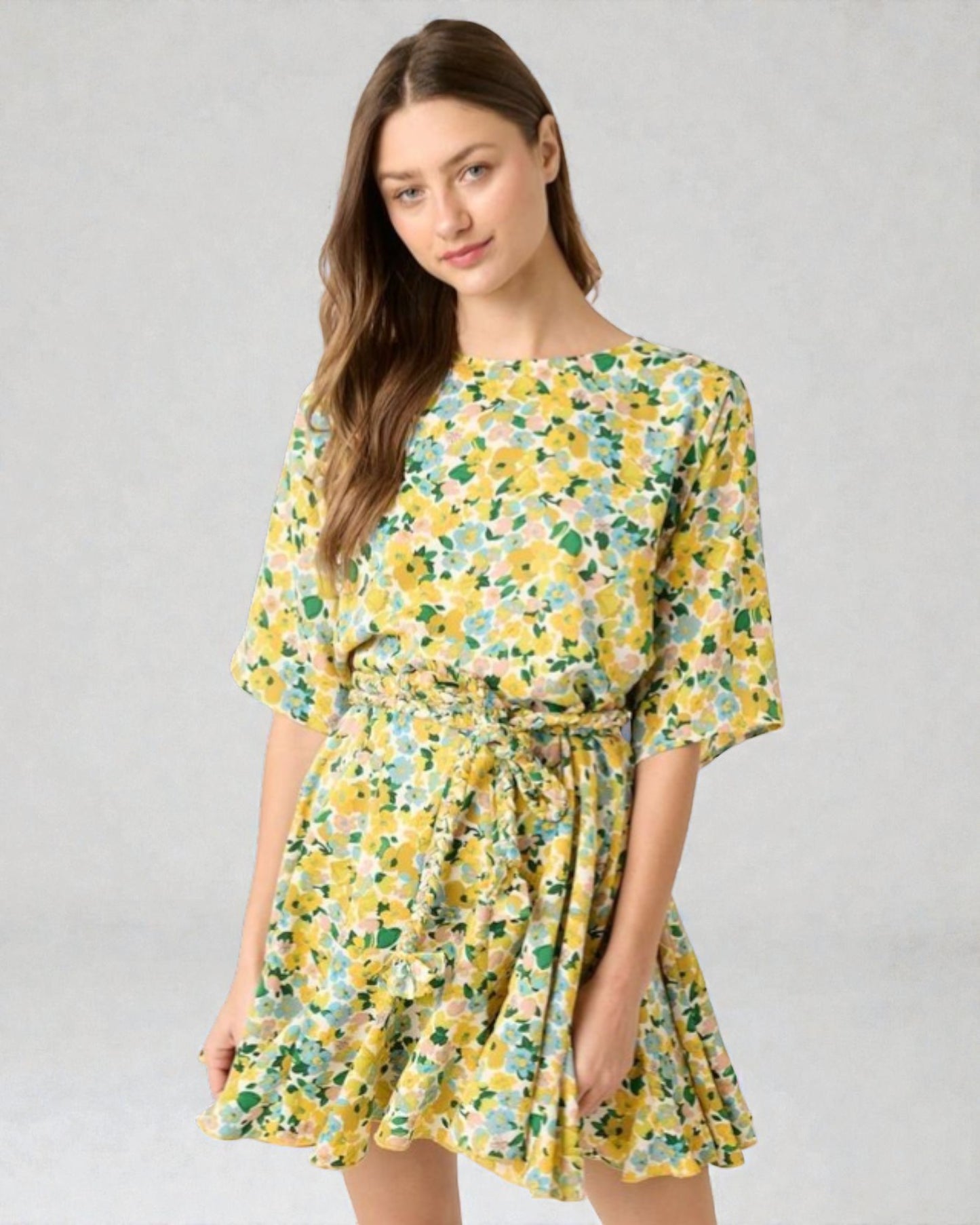 Woman wearing a yellow floral dress on a gray background