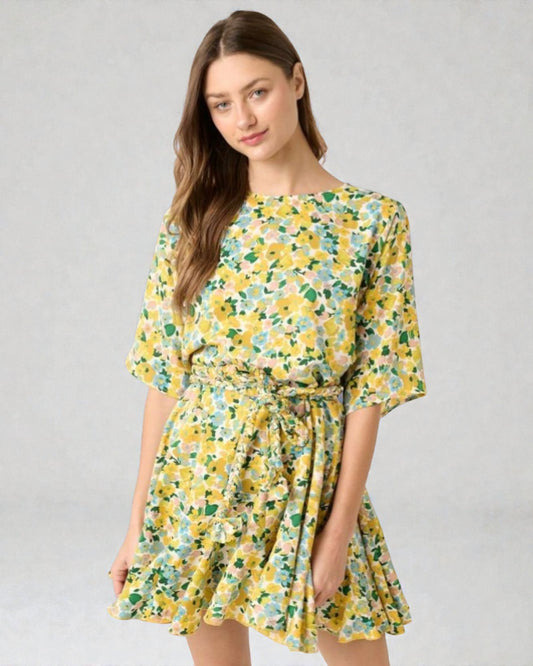 Woman wearing a yellow floral dress on a gray background