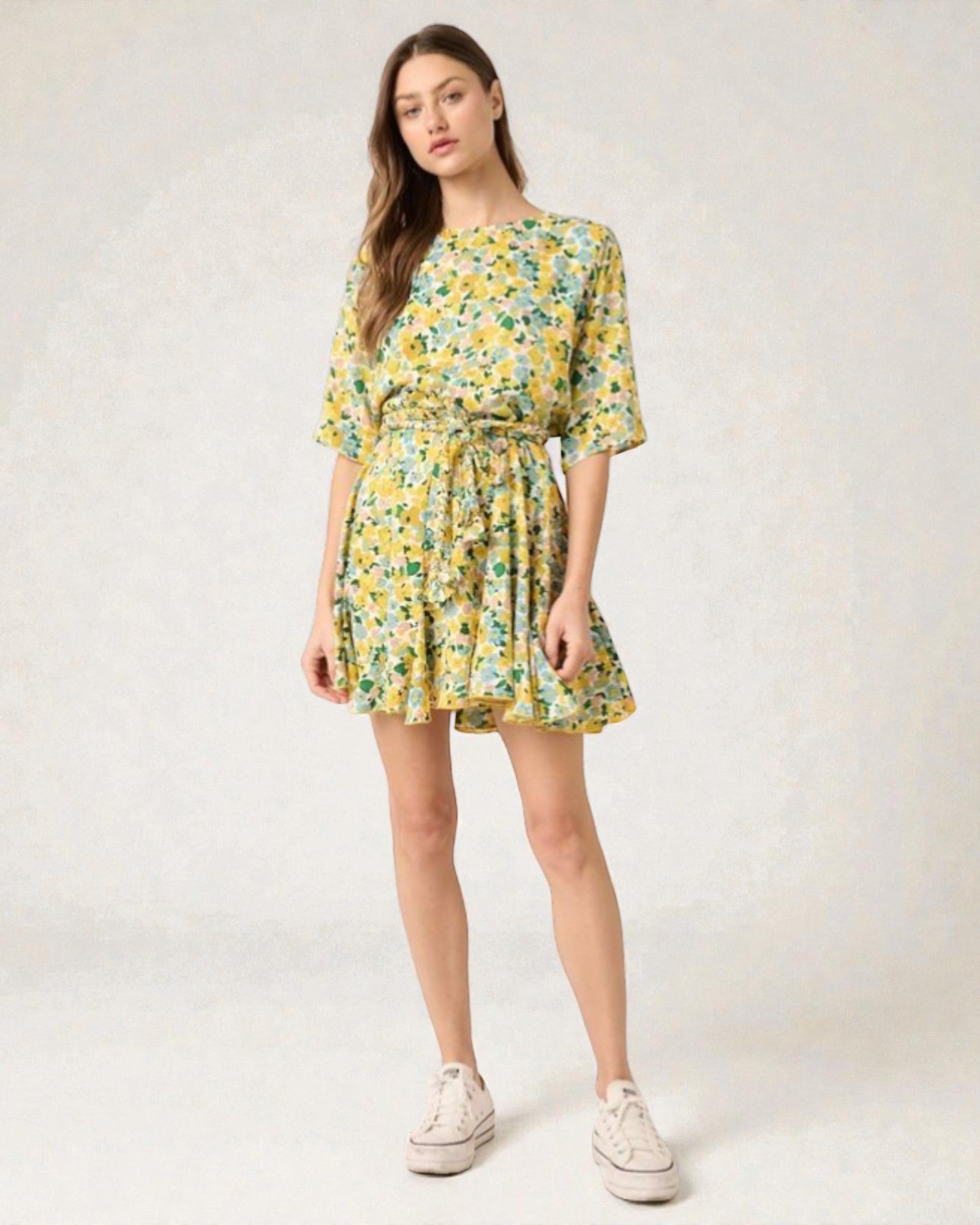 Woman wearing a yellow floral dress on a white background