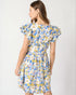 Woman wearing a floral dress with blue, yellow, and white colors on a plain background