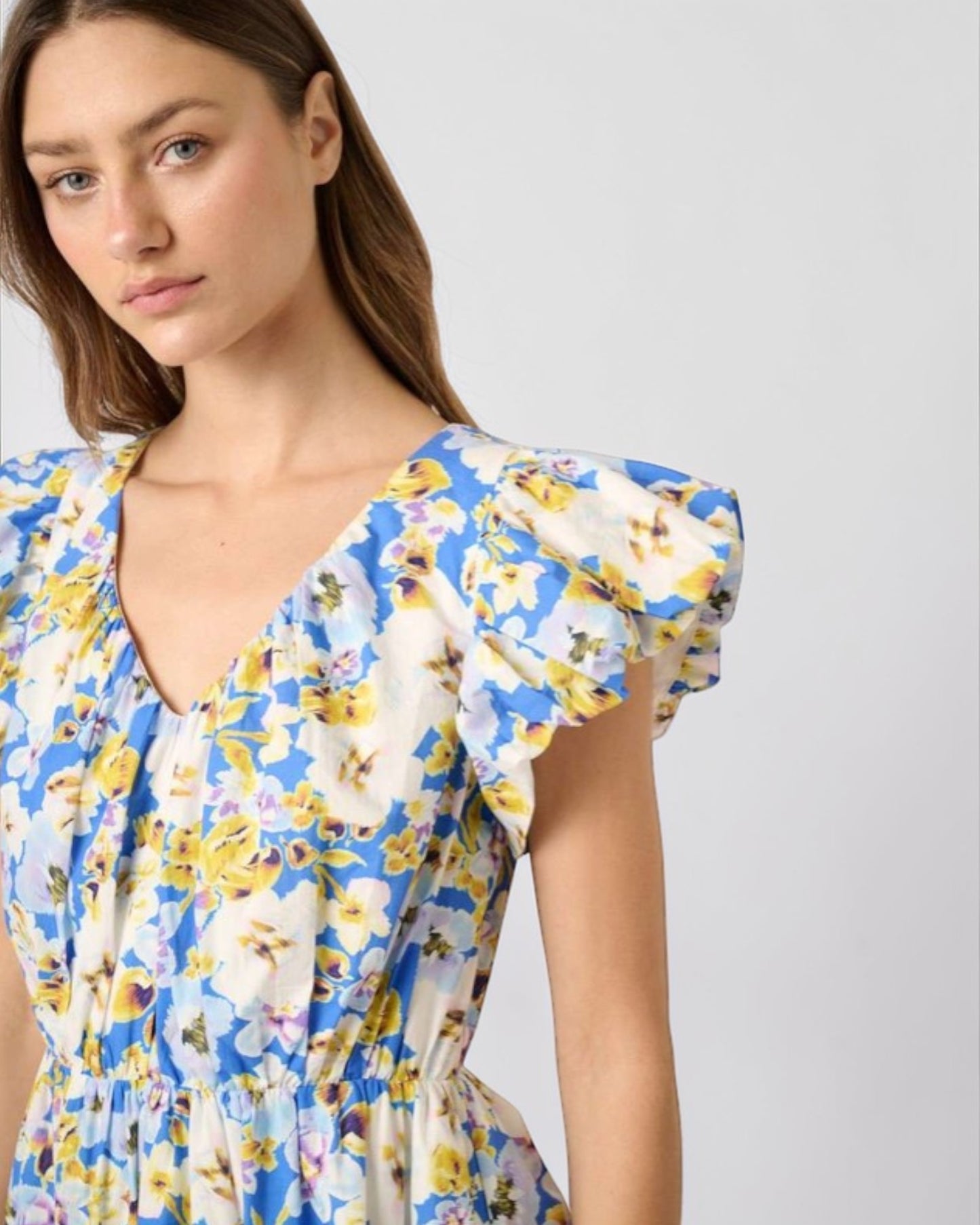 Woman wearing a blue floral dress against a plain background