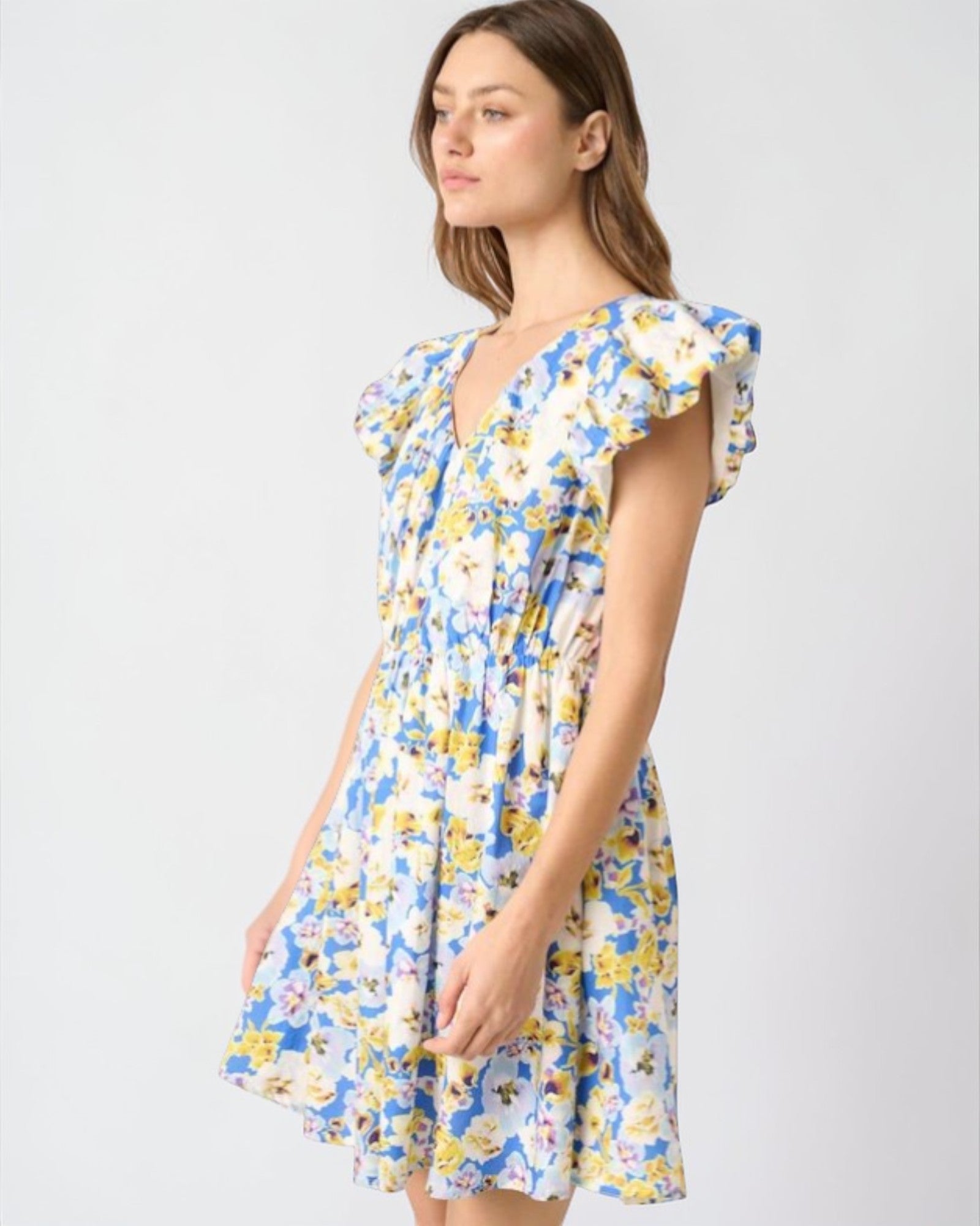 Woman wearing a floral dress with ruffled sleeves on a white background