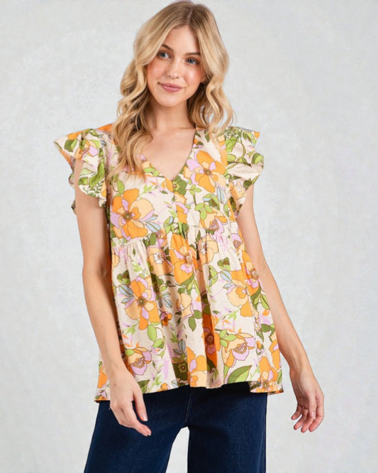 Woman wearing a floral top with ruffled sleeves on a plain background