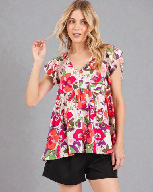 Woman wearing a colorful floral blouse against a gray background