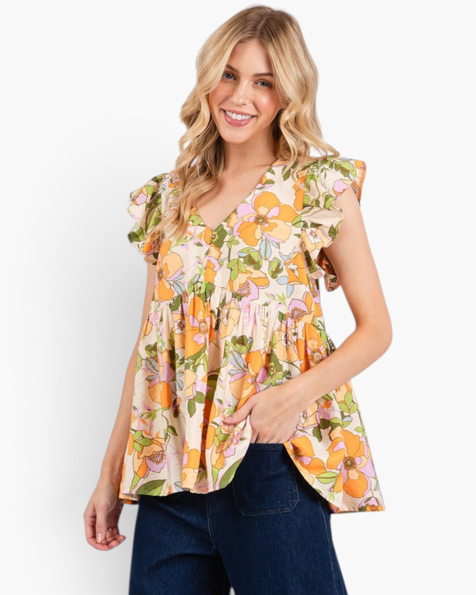A woman wearing a sleeveless peplum-style blouse with a colorful floral print in orange, yellow, pink, and green on a light beige background, paired with dark blue jeans, against a plain white studio background.