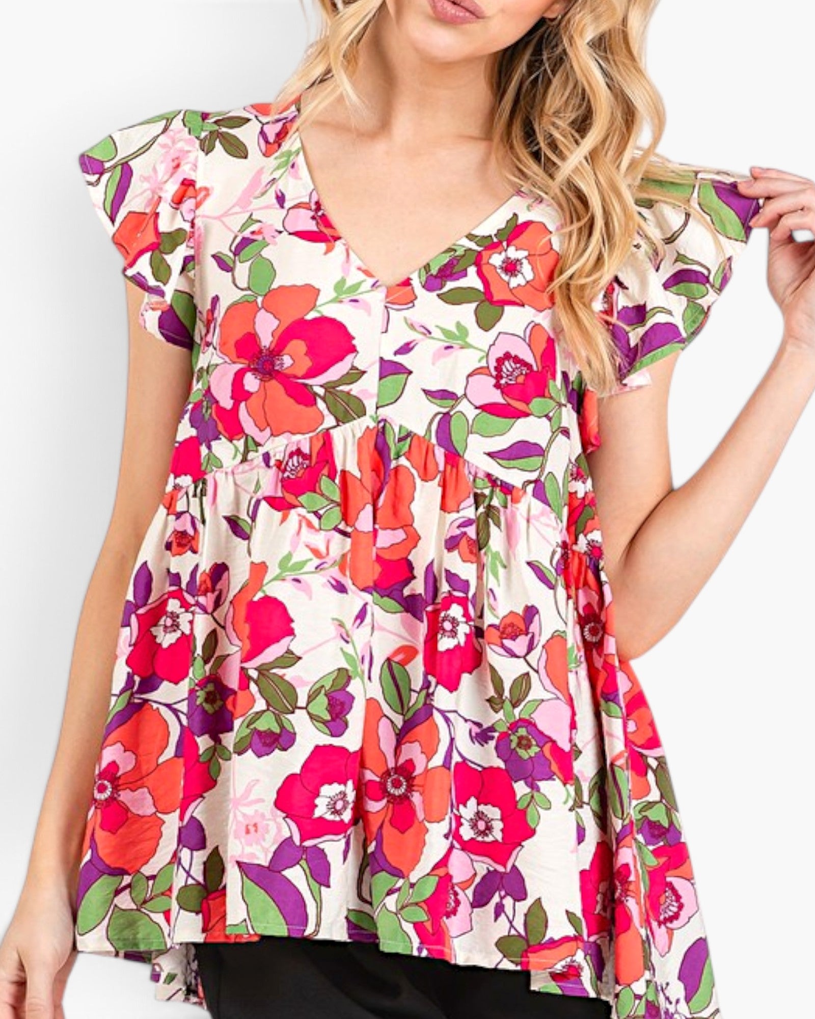 A woman wearing a short-sleeve V-neck top with a colorful floral print, featuring red, pink, orange, and green flowers on a light background.