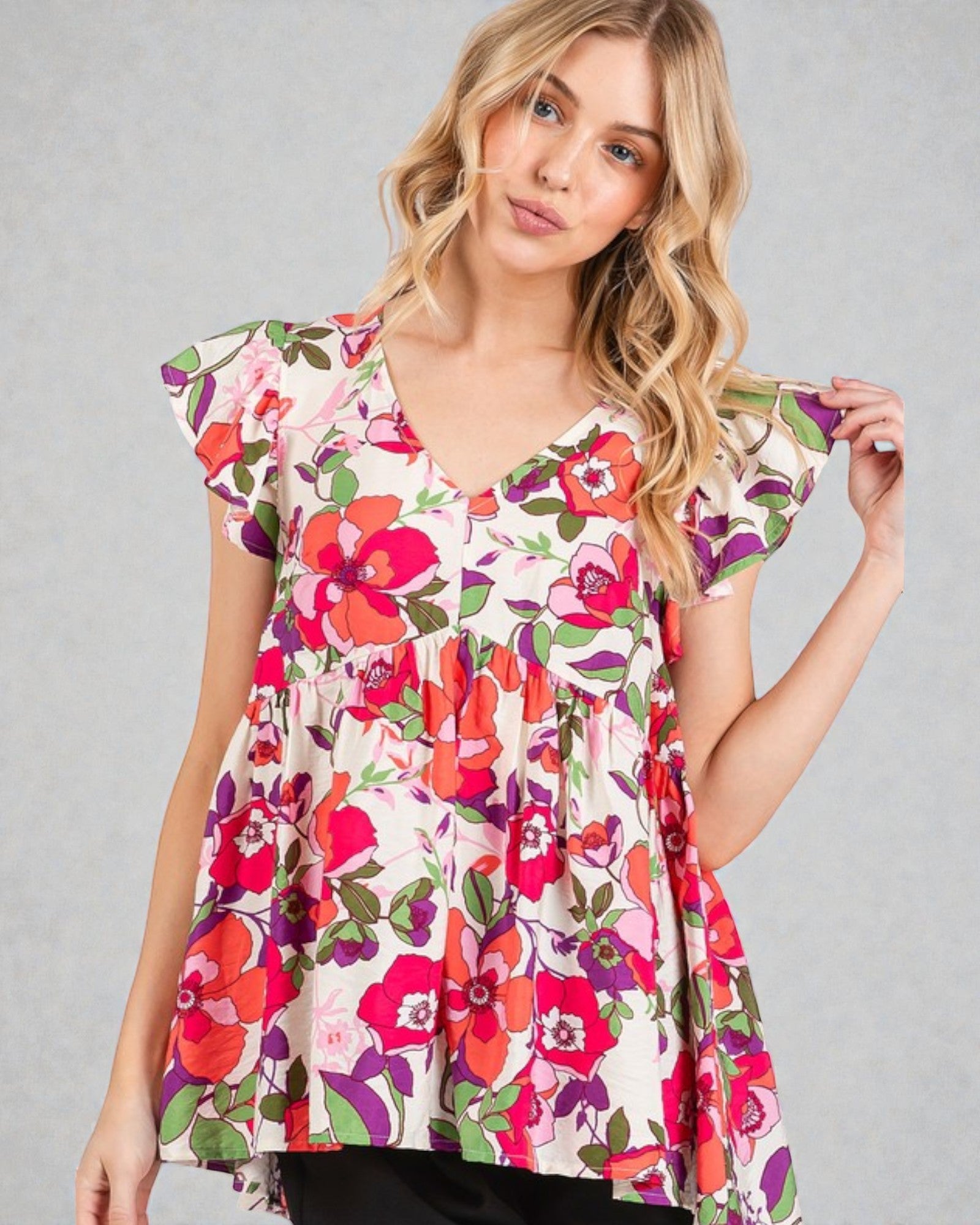 Woman wearing a colorful floral blouse against a gray background