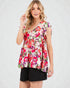 Woman wearing a colorful floral blouse with black shorts on a white background