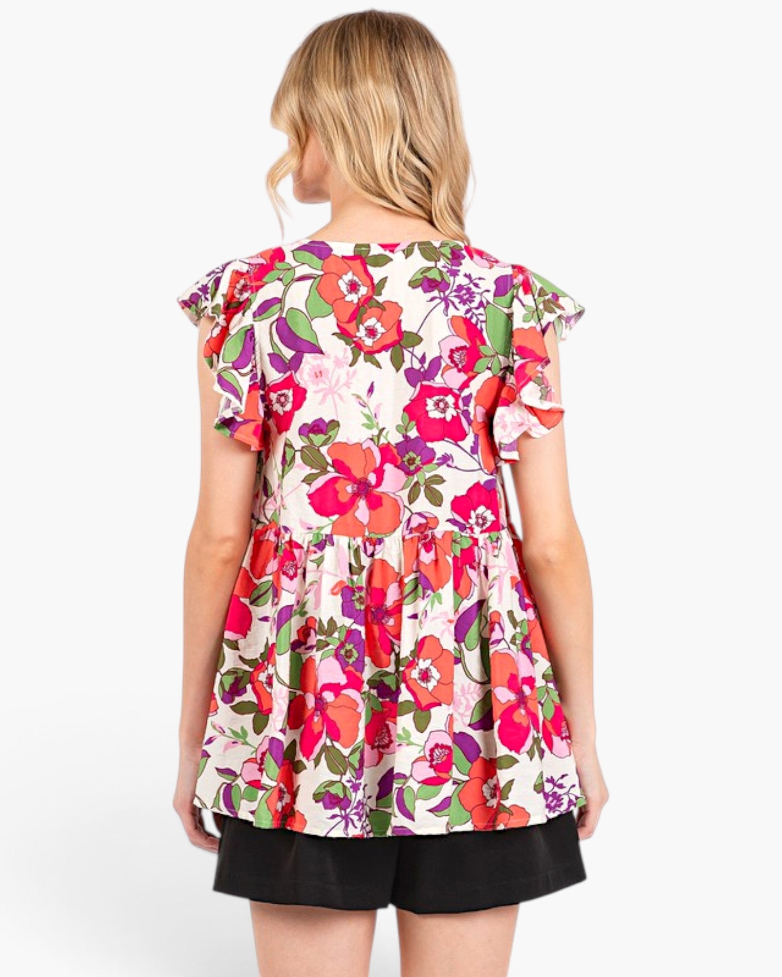 A woman shown from the back wearing a short-sleeve floral peplum top with black shorts, against a plain white studio background.