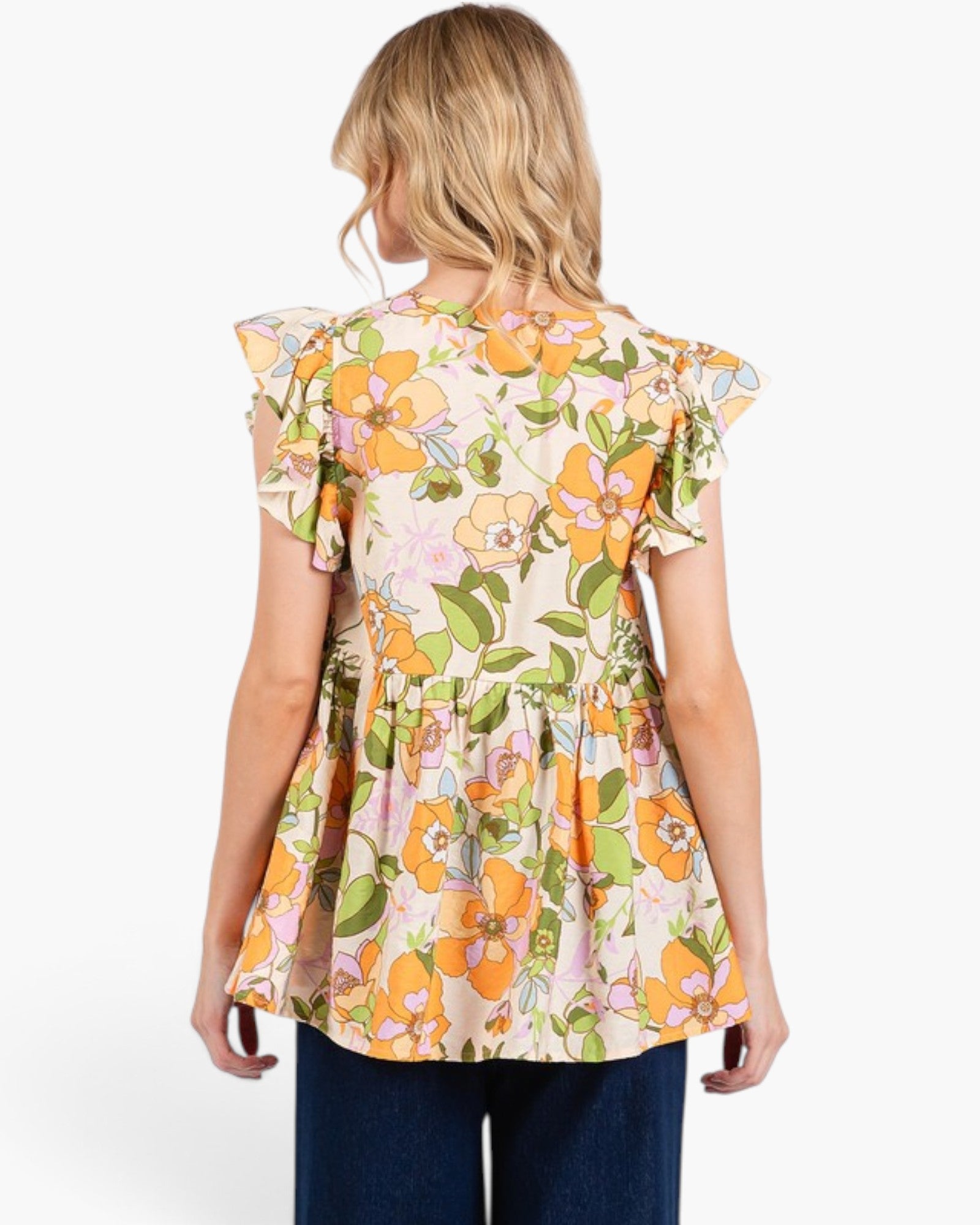 A woman viewed from the back wearing a short-sleeve peplum top with a colorful floral print on a cream background, paired with dark blue jeans, against a plain white studio background.