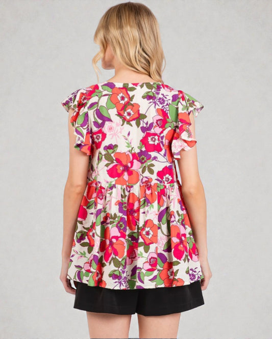 Woman wearing a colorful floral dress with ruffled sleeves on a gray background