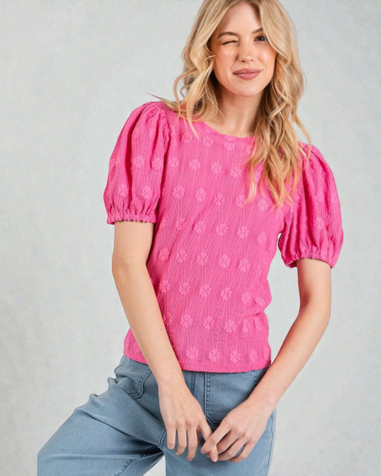 Woman wearing a pink blouse with puff sleeves against a gray background