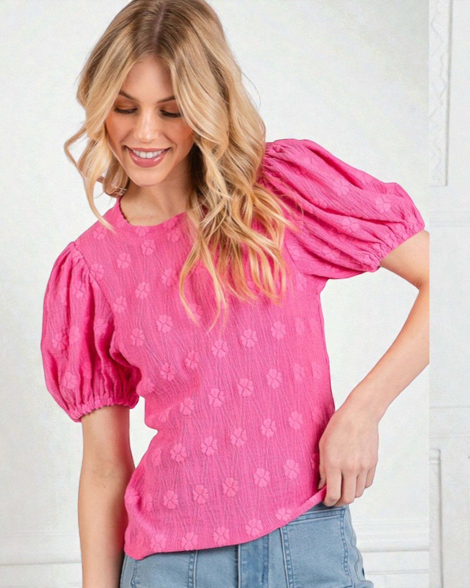 Woman wearing a pink blouse with puff sleeves against a white background