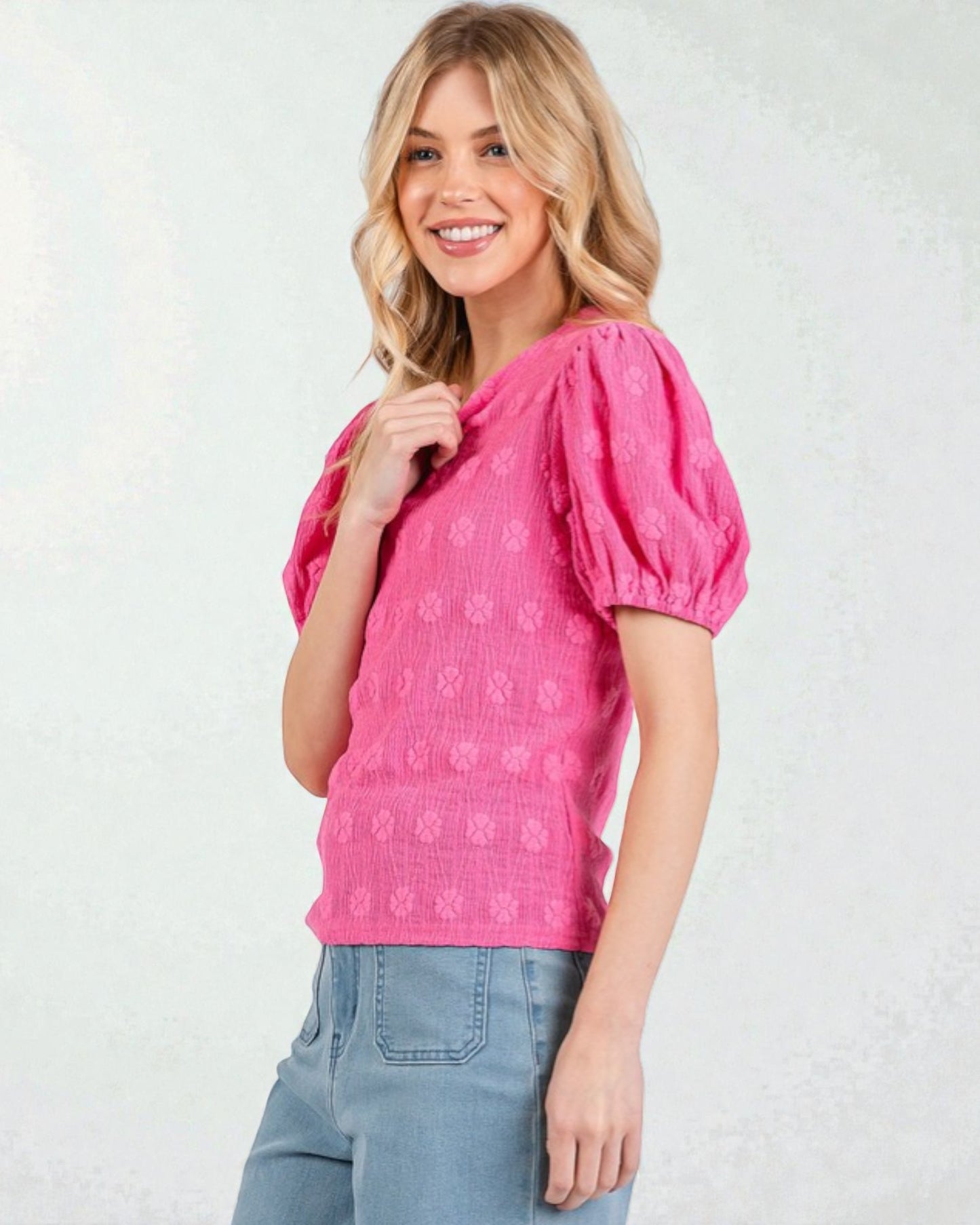 Woman wearing a pink blouse with puff sleeves against a white background