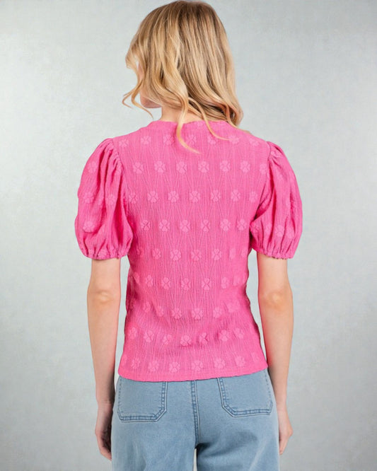 Person wearing a pink blouse with puff sleeves on a gray background