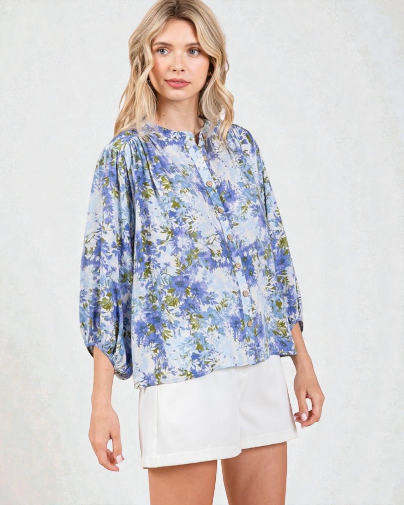 Woman wearing a blue floral blouse and white skirt on a light background