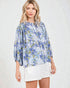 Woman wearing a blue floral blouse and white skirt on a light background