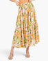 A model wearing a tiered, A-line midi skirt with a vibrant orange, green, and pink floral print on a cream background, paired with beige heeled sandals against a light gray studio background.