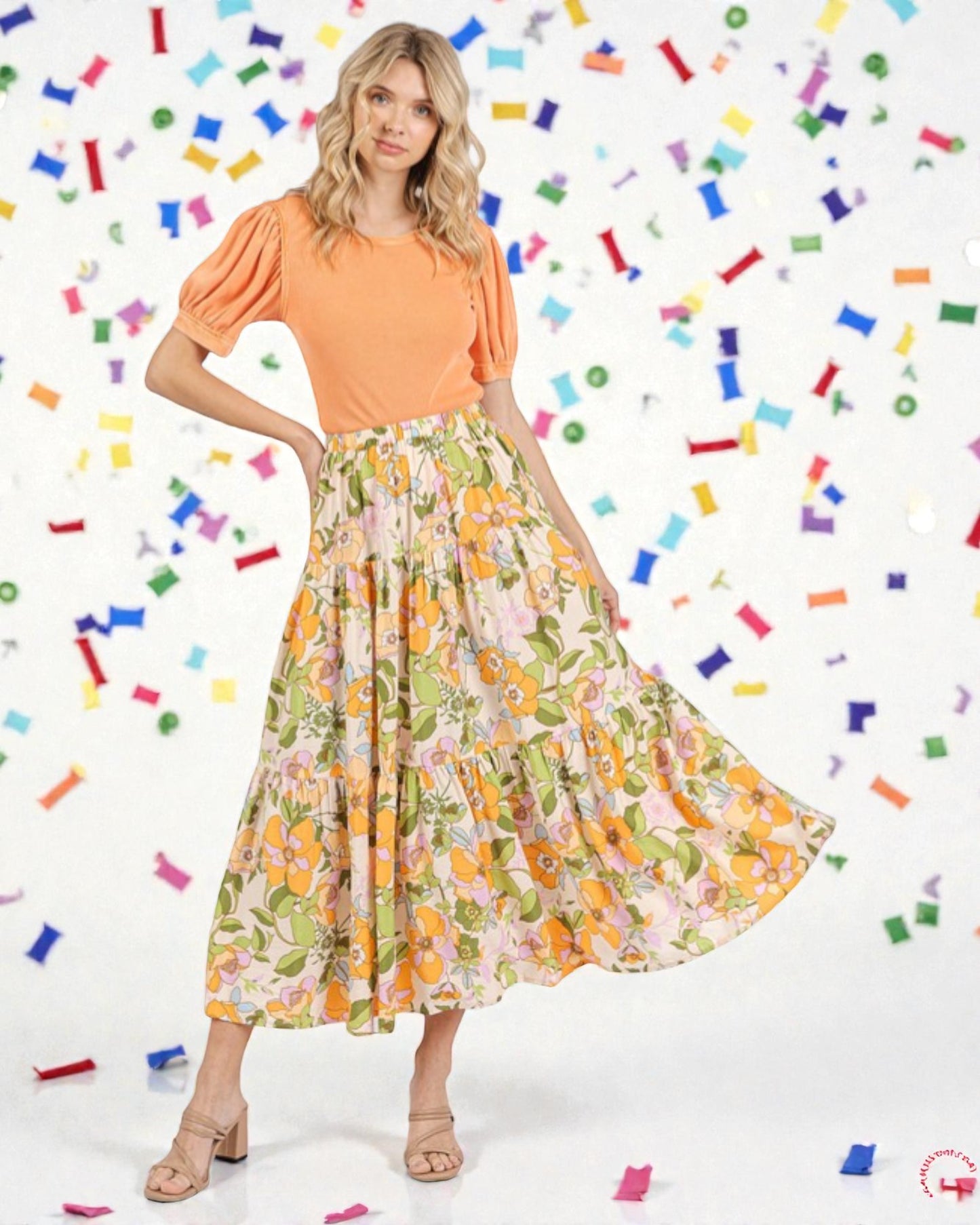 Woman wearing an orange top and floral skirt with colorful confetti background