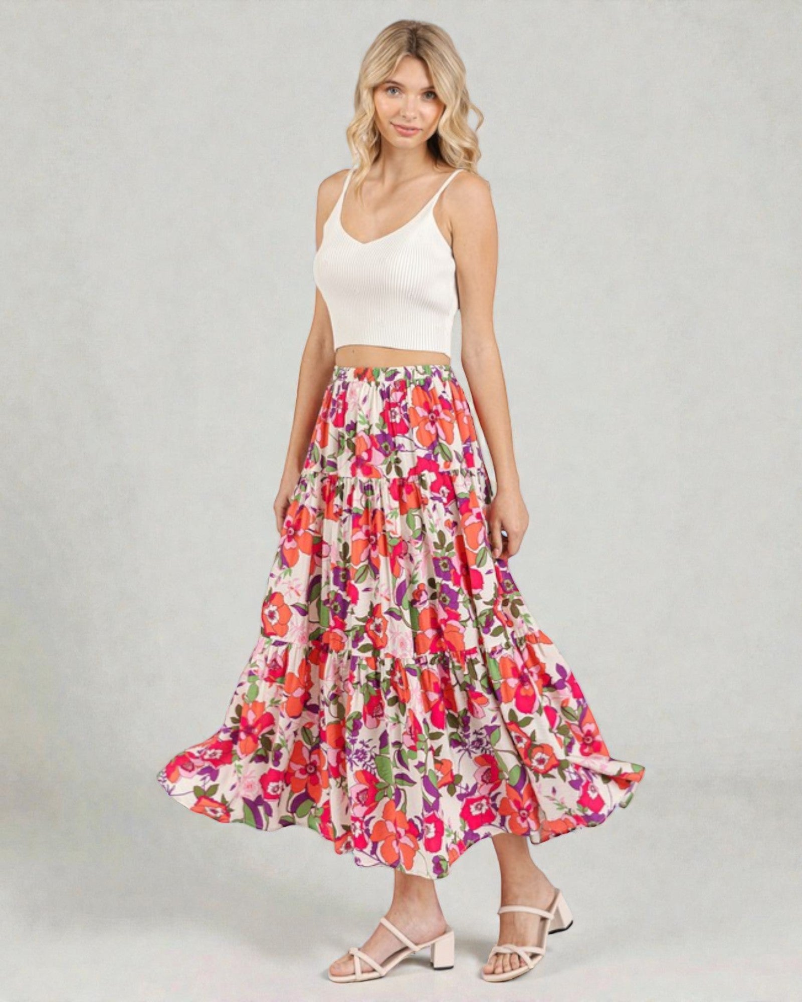 Woman wearing a floral skirt and white top on a gray background