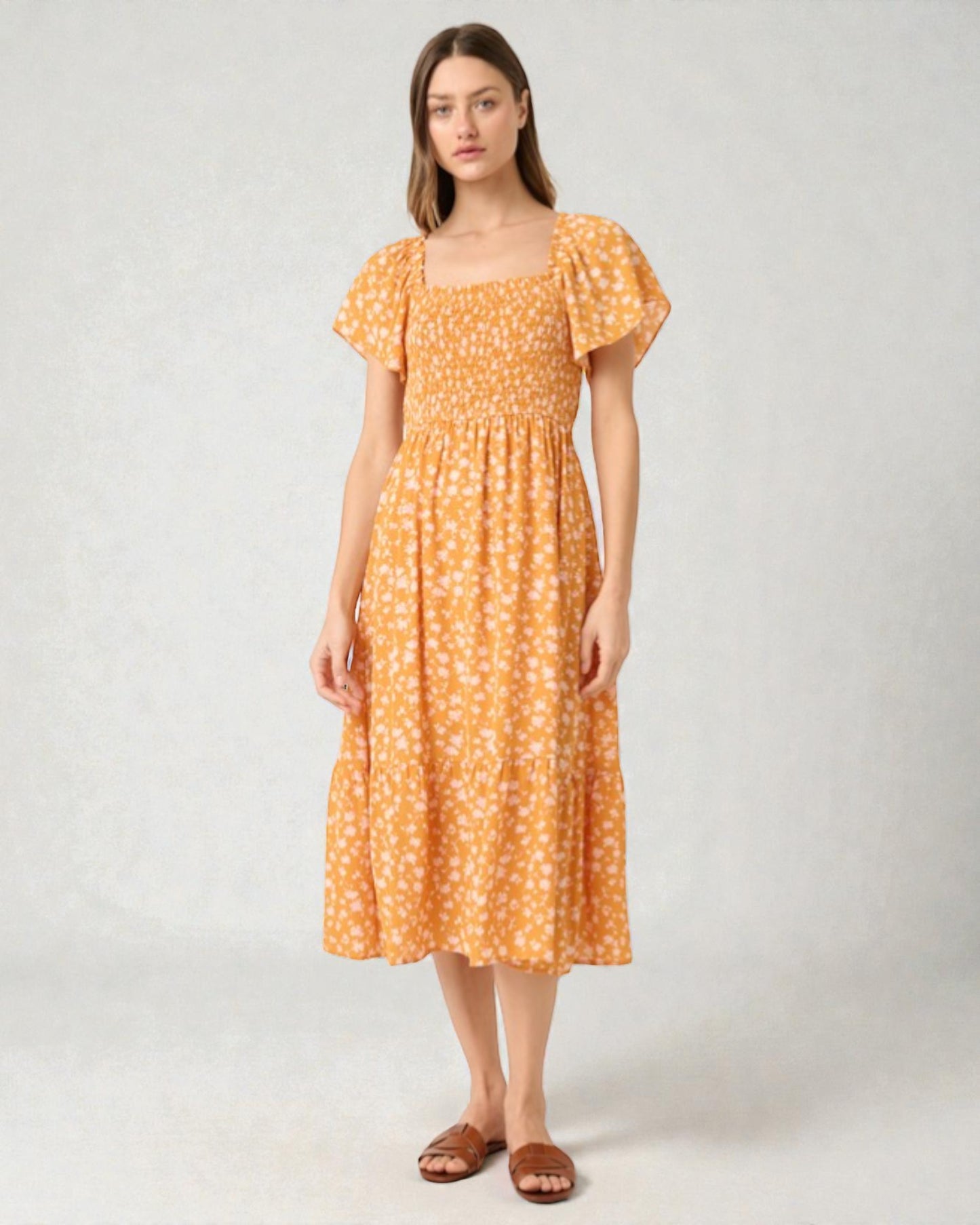 Woman wearing an orange floral dress on a white background