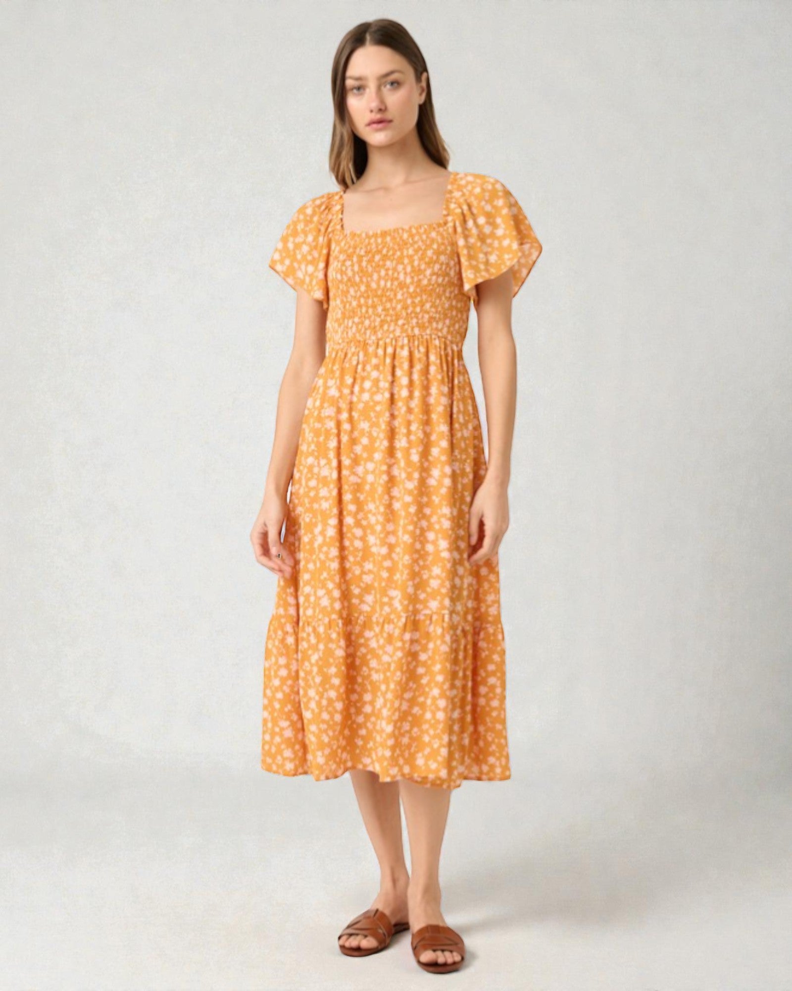 Woman wearing an orange floral dress on a white background