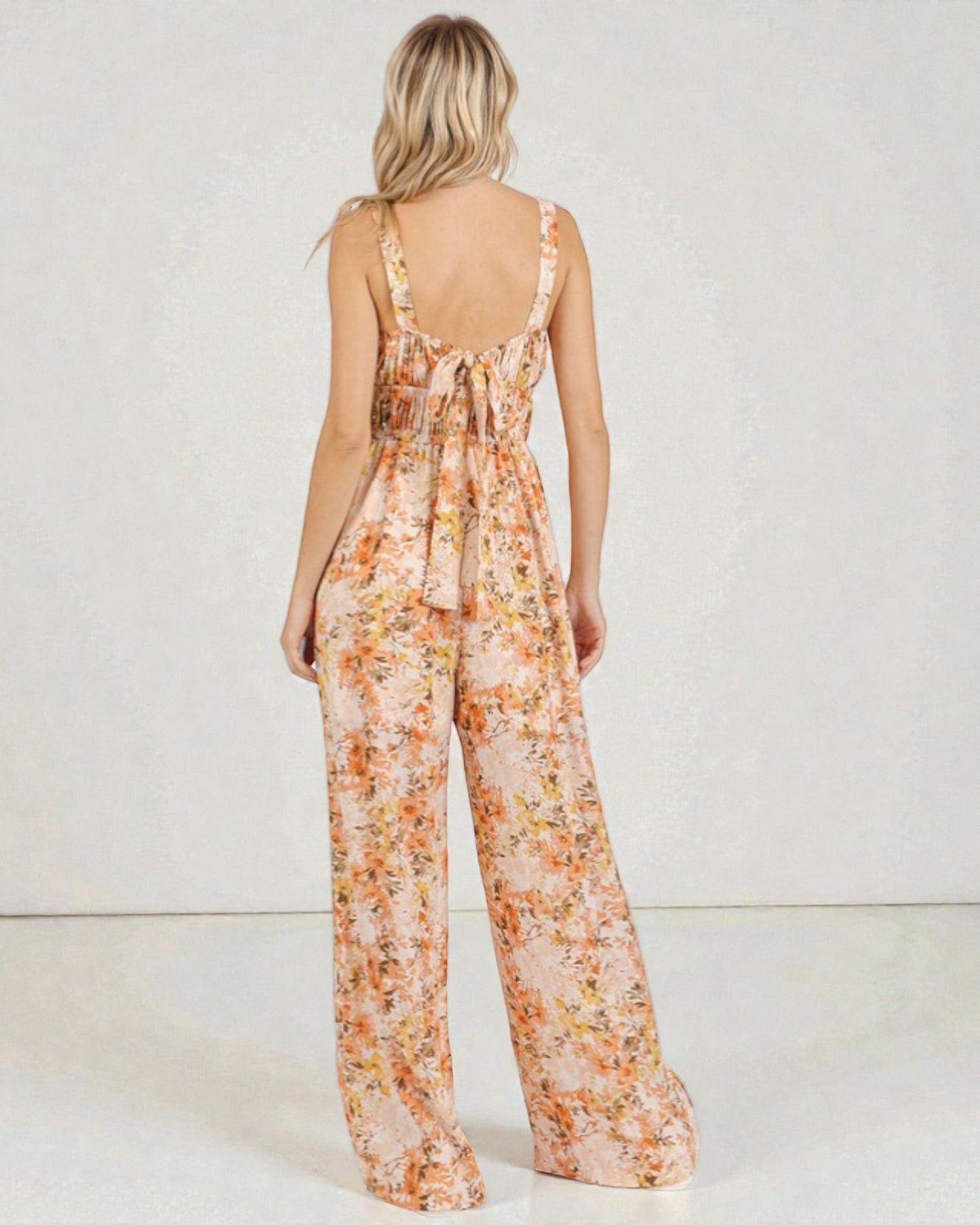 Woman wearing a floral jumpsuit on a plain background