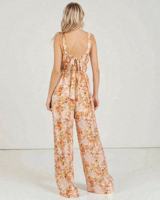 Woman wearing a floral jumpsuit on a plain background