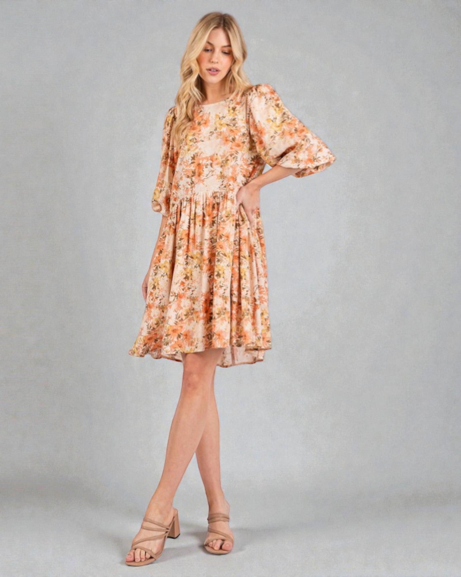 Woman wearing a floral dress with bell sleeves on a plain background