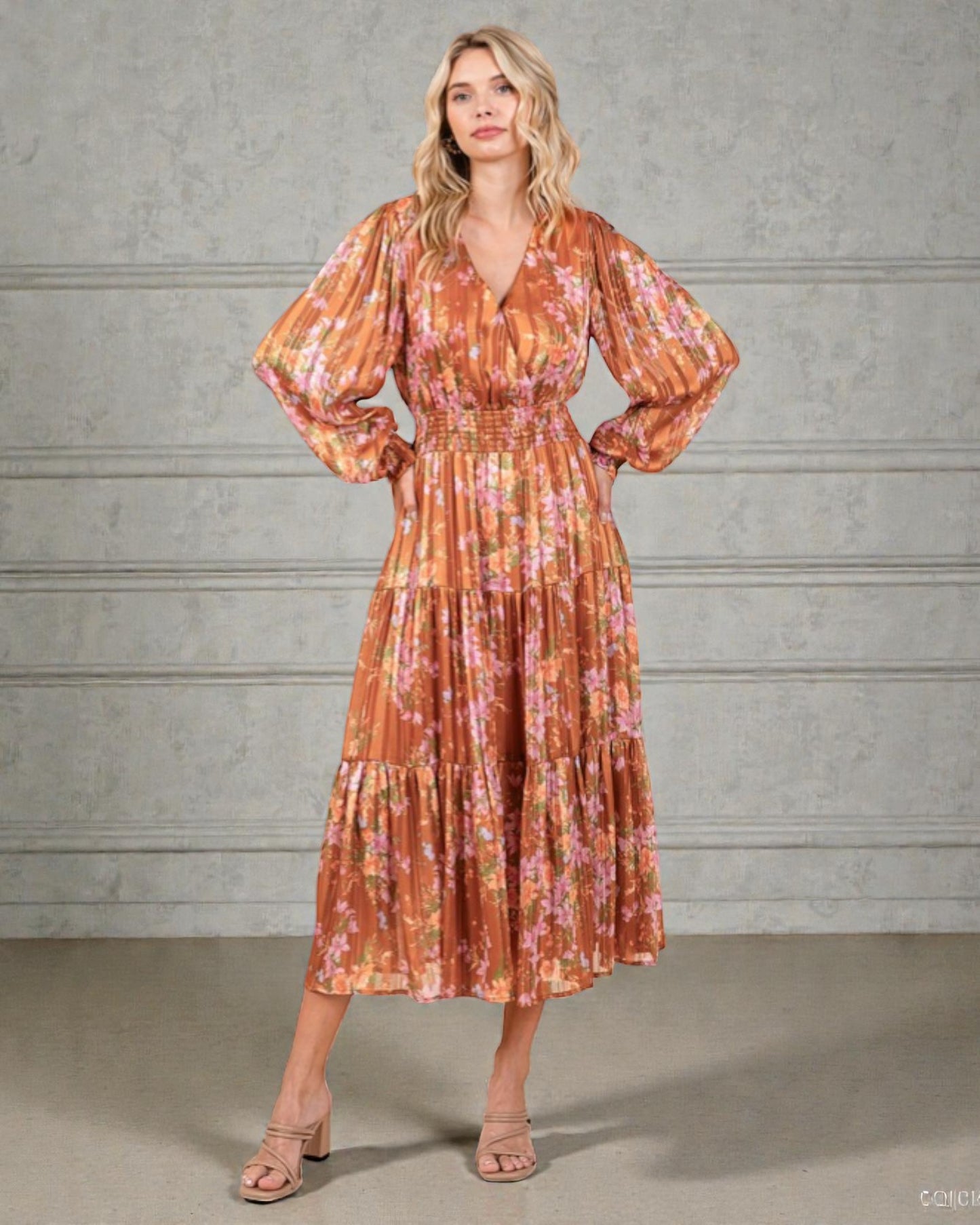 Woman wearing a floral dress against a gray concrete wall.